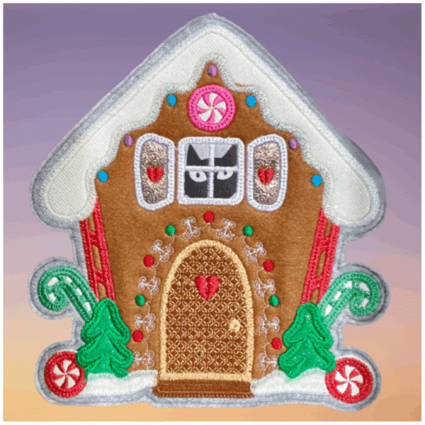 Ein gesticktes Lebkuchenhaus mit bunten Verzierungen, zwei grünen Zuckerstangen und Weihnachtsbäumen auf einem hellvioletten Hintergrund.