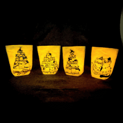 Vier beleuchtete Lichtbeutel mit Katzen-Weihnachtsmotiv auf dunklem Hintergrund. Jedes Windlicht zeigt unterschiedliche Katzenzeichnungen, darunter Katzentürme und ein Katzenduo.