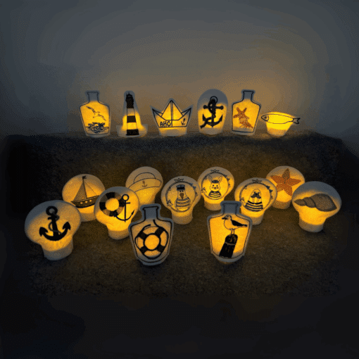 Eine Sammlung von leuchtenden Dekorationen mit maritimen Motiven. Die Lichter sind in verschiedenen Formen wie Flaschen, Ankern und Booten gestaltet und erzeugen eine warme und gemütliche Atmosphäre.