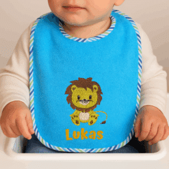 Baby trägt Wörner Lätzchen mit Löwen-Motiv und Name Lukas