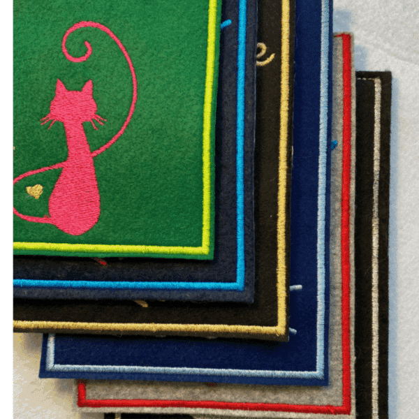 Impfausweishülle aus Filz für Katzen: Übereinandergelegte Filz-Impfausweishüllen mit verschiedenen Farben und Katzenmotiven. Sichtbar hier der einfarbige Rand.