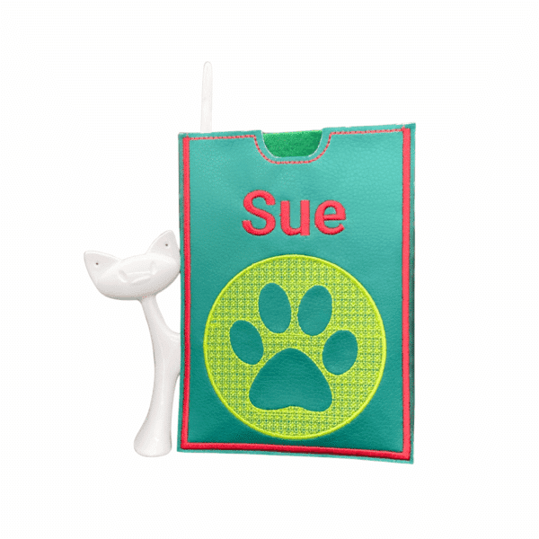Grüne Impfausweishülle aus Kunstleder für Hunde mit dem Namen Sue und gelber Pfotenstickerei.