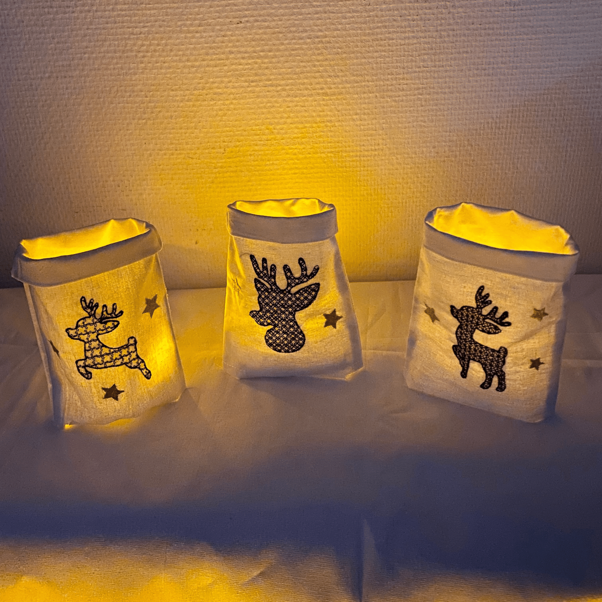 Drei leuchtende Lichtbeutel mit Rentieren als festliche Dekoration, ideal für stimmungsvolle Weihnachtsbeleuchtung.