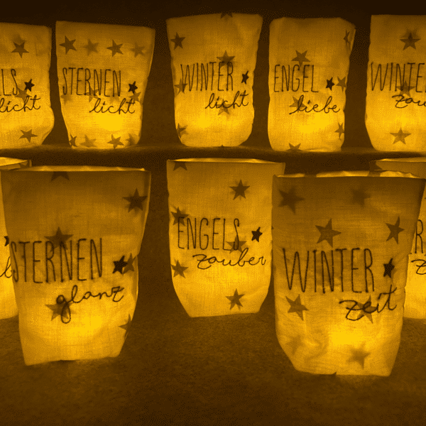 Kombinierte Ansicht mehrerer Lichtbeutel mit winterlichen Schriftzügen in zwei Reihen und warmem Licht