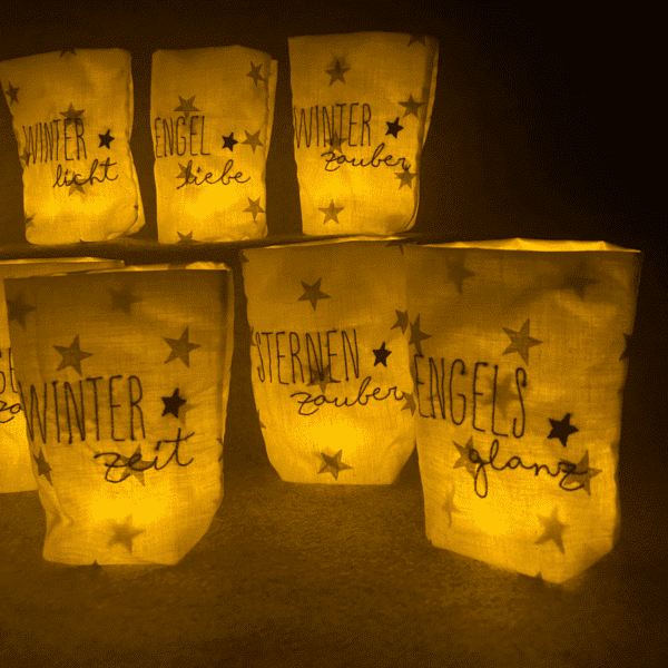Detailansicht leuchtender Lichtbeutel mit winterlichen Schriftzügen wie „Winterzeit“ und „Engelsglanz“