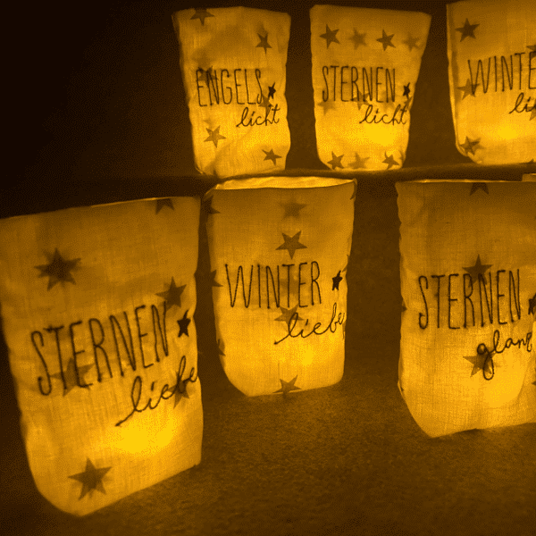 Seitliche Ansicht von Lichtbeuteln mit winterlichen Schriftzügen wie „Winterliebe“ und „Sternenliebe“