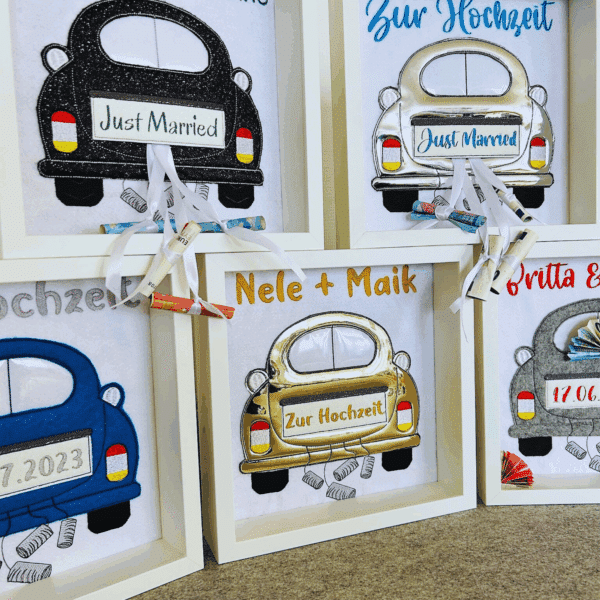 Nahansicht vom Geldgeschenk zur Hochzeit mit fünf verschiedenen Bilderrahmen, bestickt mit Namen, Datum und dem Kennzeichen.