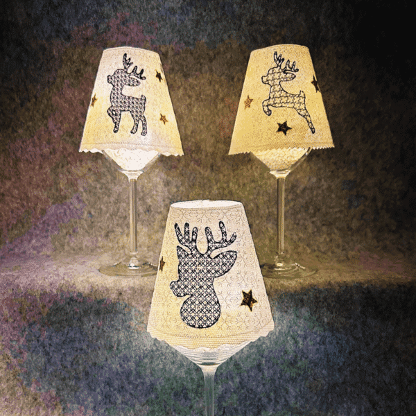 Lampenschirm Weinglas mit Weihnachtsmotiven – Rentier-Designs mit goldenen Sternen, beleuchtet für festliche Stimmung.