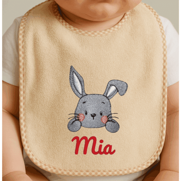 Personalisierte und bestickte Baby Lätzchen in Beige mit niedlichem Hasenmotiv und rotem Namensstick „Mia“, liebevoll gefertigt als individuelles Geschenk für Babys.