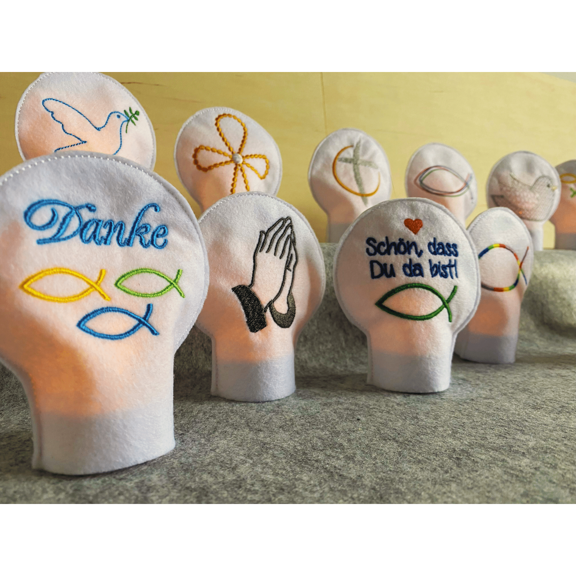 Teelichtcover mit christlichen Motiven aus Filz – bestickte LED-Deko im Tageslicht für kirchliche Feiern