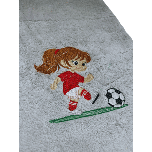 Fußballhandtuch mit Kinder-Motiv und Name: Detailaufnahme eines Fußballhandtuchs mit Kinder-Motiv – Mädchen im roten Trikot spielt Fußball