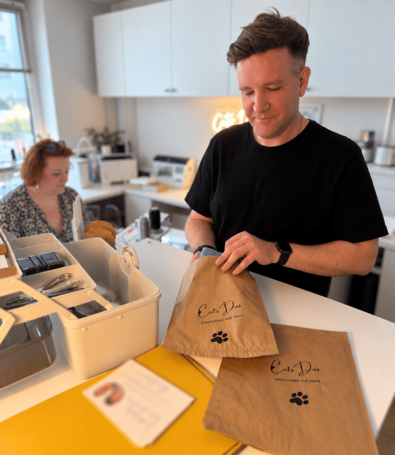 Moritz verpackt eine Bestellung in einer CatsDus Papiertüte im Atelier.